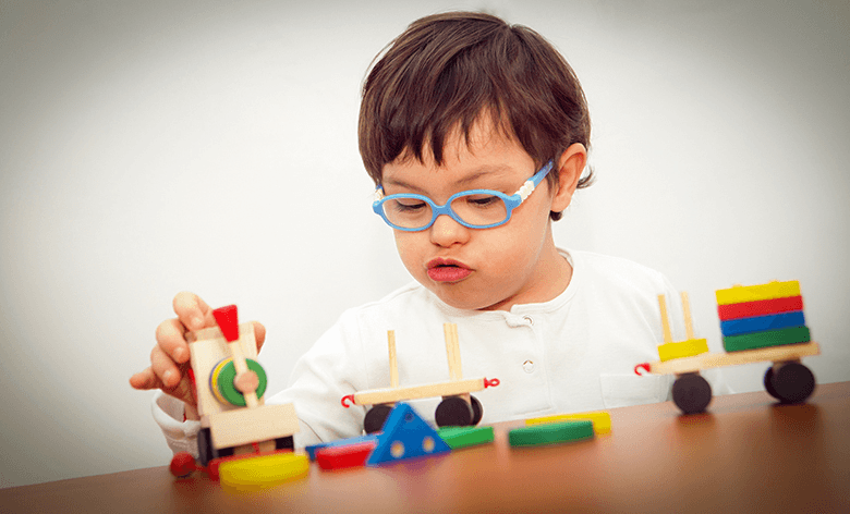 Niño de tres años con discapacidad jugando con un tren.